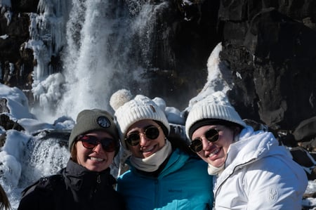 Happy clients smiling in front of the Öxarárfoss waterfall