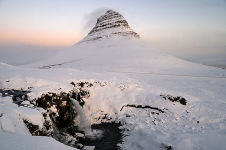 The Mount Kirkjufell in front of a partially frozen waterall - Snæfellsnes small group tour