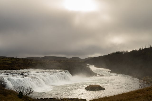 A man is fishing in front of a beautiful icelandic waterfall