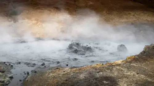 Une flaque de boue bout au milieu de roches couvertes de souffre