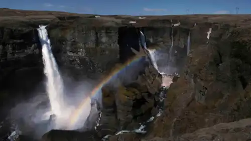 Deux magnifiques chutes d'eau se jettent dans un canyon alors qu'un arc-en-ciel se dessine dans le brouillard des cascades