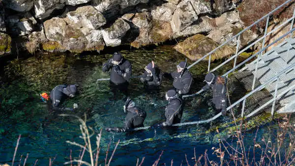 Personnes en combinaison sèche, s'apprêttent à renter dans une eau transparente