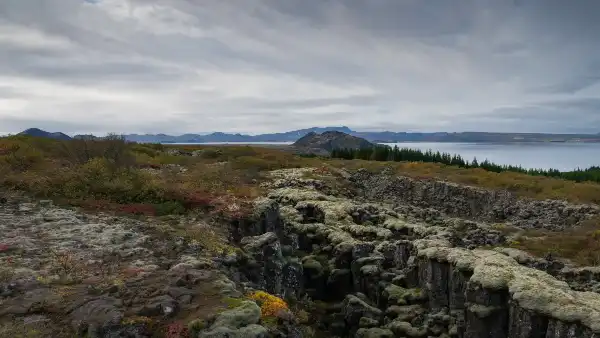 magnifique paysage avec une fissure tectonique couverte de mousse, des couleurs automnales et un lac en arrière plan