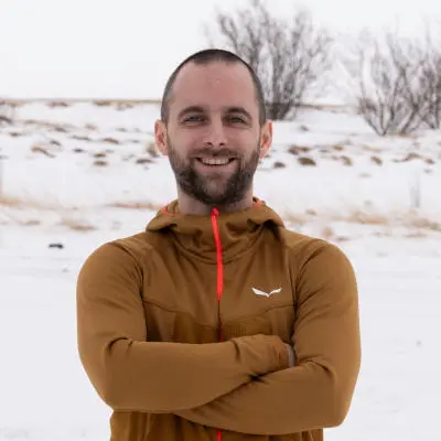 guide smiling at the camera with arm crossed, in the winter