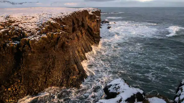 Sunrise over cliffs dominating an agitated ocean