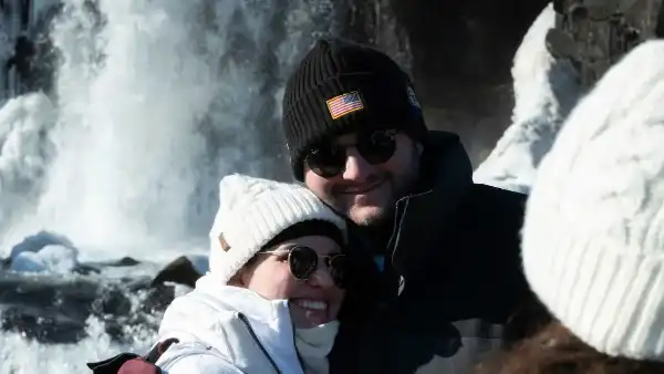 Two Happy tourists smiling in front of a waterfall