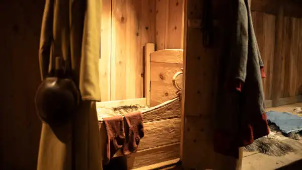 A tiny, cozy, wooden nook with a bed nested in it