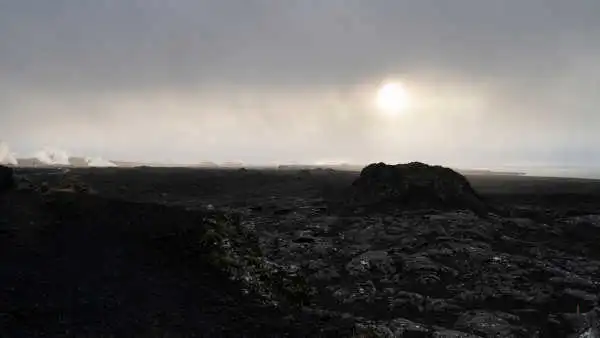 Two black volcanic craters are photographed before sunset