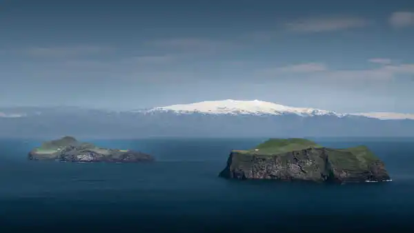 Panorama of a glacier covering a volcano with a few islands in the foreground