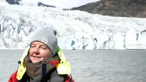 Someone enjoys the sunshine on a boat next to icebergs