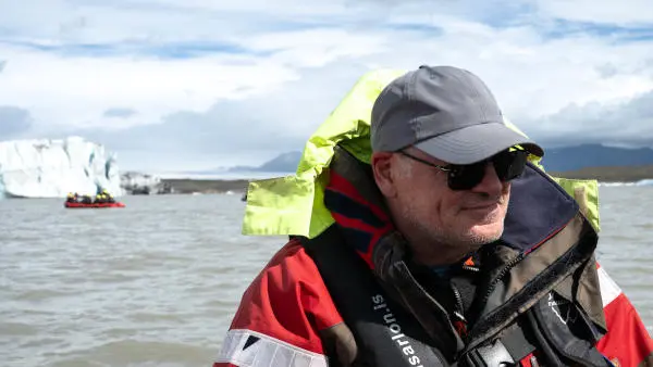 Someone on a boat enjoy the sun in front of a glacier