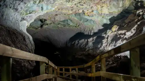 Some wooden stairs are going deep down a volcanic cave