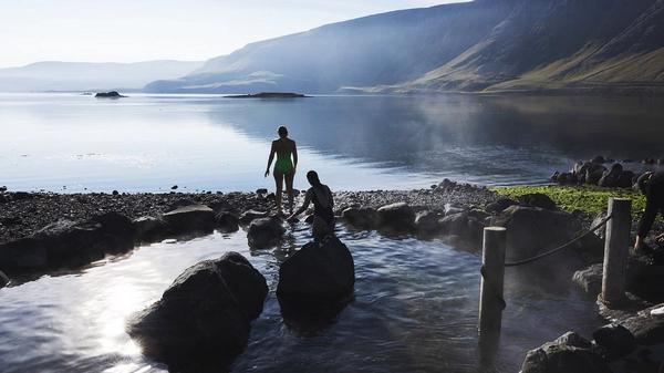 People enjoying a hot bath next to the cold ocean