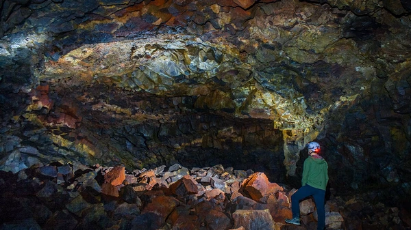 Cavers with headlamps exploring vast Raufarhólshellir lava tube chambers