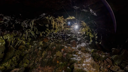 Underground adventurers exploring dramatic Raufarhólshellir lava tunnel formations