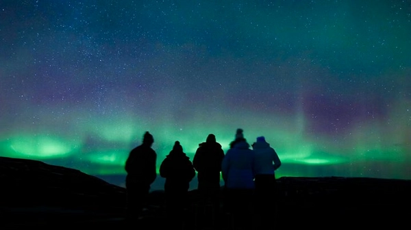 Small group of aurora hunters enjoying hot chocolate under the Northern Lights