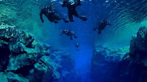Snorkelers swimming between tectonic plates in Silfra fissure's crystal-clear water