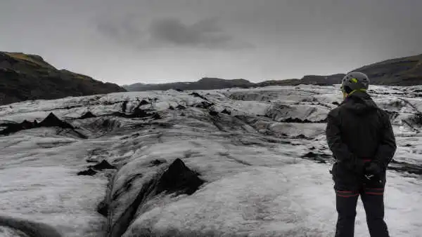 A man standing on ice looks at the glacier