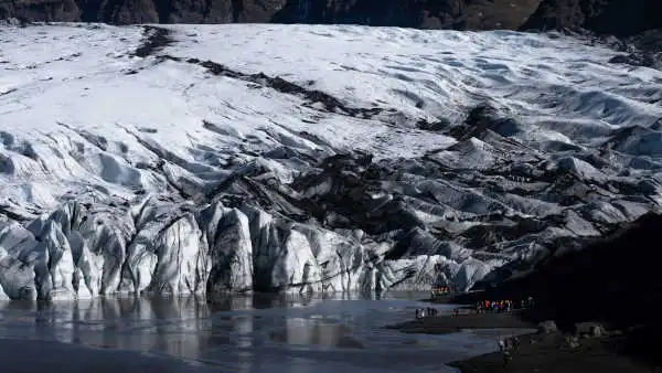 Closeup of the end of the glacier, with a group of people about to go hking on it