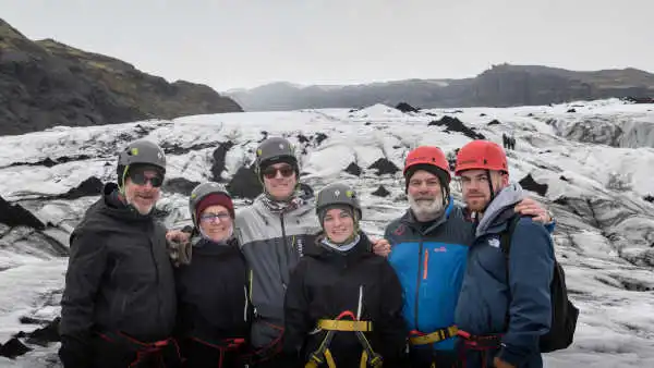 A family is posing and smiling on a glacier