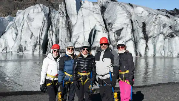 A happy family in glacier hiking gears is posing in front of a glacier