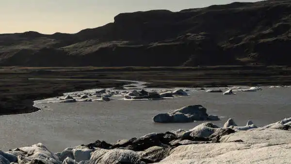 The sun is setting on a glacier lake and icebergs