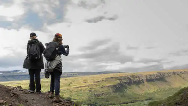 Two people on a hike are enjoying magnificient vistas over a fjord