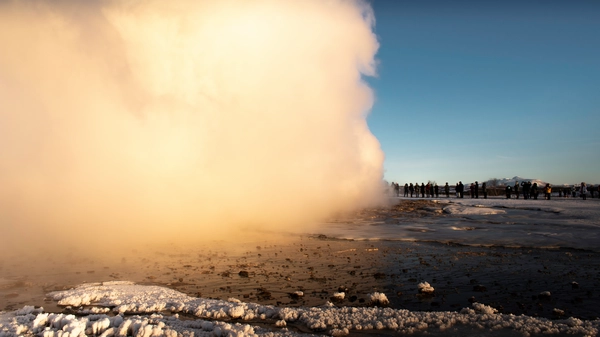 An icelandic geyser is blowing in front of a crowd on the golden circle