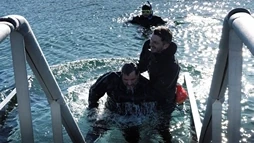 A client is being pulled out of the water by the diving instructor