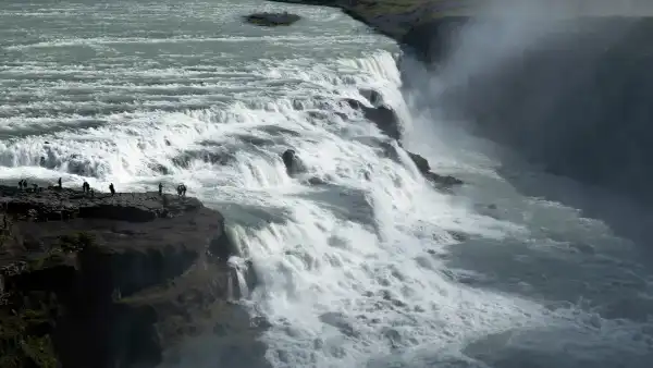 Close up of a waterfall with people standing on the side of it 