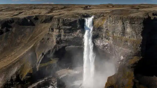 A tall waterfall falls straight along cliffs