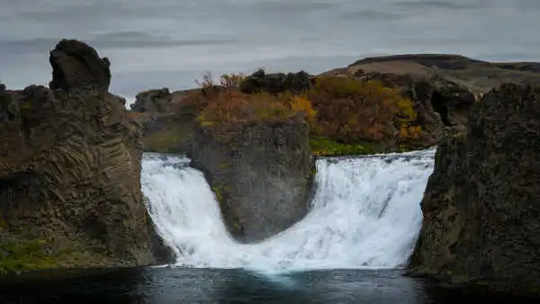 Two waterfalls are flowing down into a clear lake