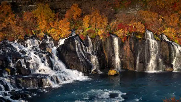 Beautiful waterfalls falling in turquoise blue water in front of fall-colored bushes