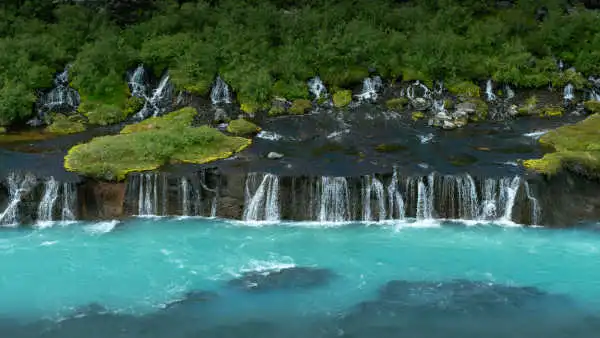 Waterfalls flows through green vegetation into turquoise blue water