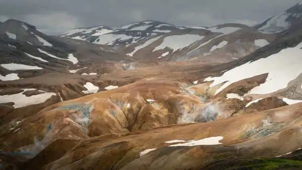 Misty day over brown and orange steaming mountains