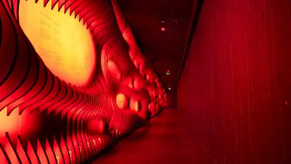 A red lit corridor with signs of the left displaying information about the different volcanoes of Iceland