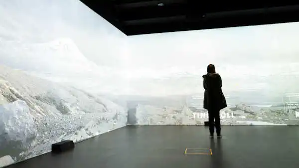 A woman stands in a room with walls covered with interactive screens