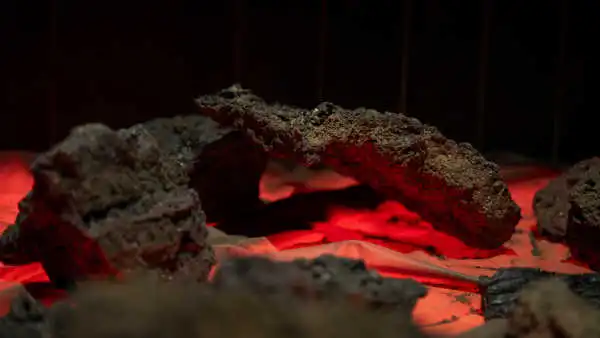 Some volcanic rocks are displayed on a red lit table