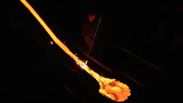 Someone holding a steel rod is playing with molten lava