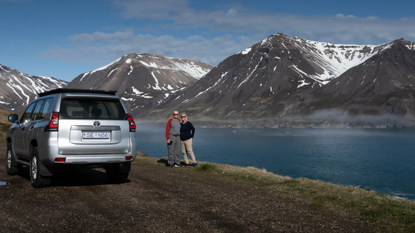 Stunning icelandic landscapes with two clients posing in front, with the guide's jeep on the left