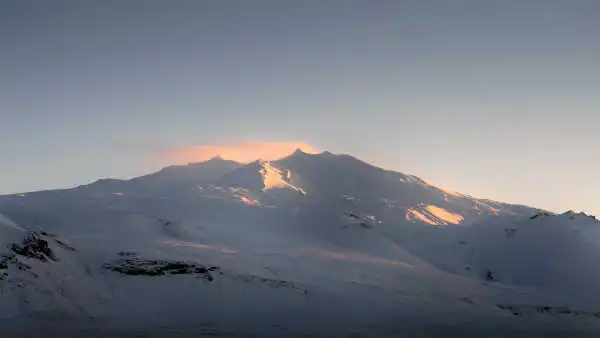 Snow covered top of a volcano-glacier, under the sunset