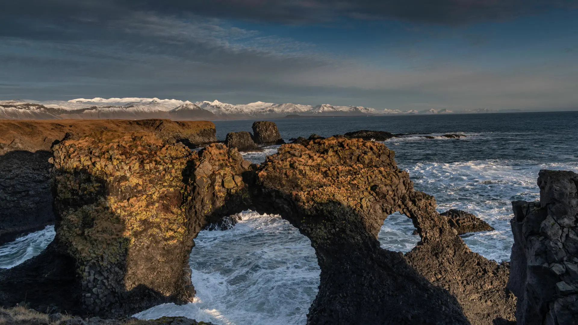 Natural stone arch over the ocean under sunset light