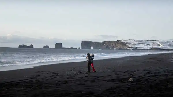 Two sisters are playing on a black sand beach