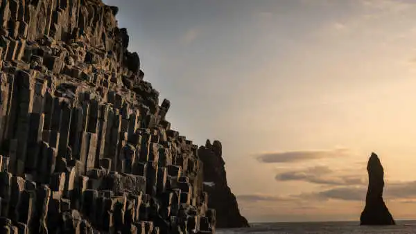 Basaltic columns, sea pillars and a black sand beach photographed under sunset