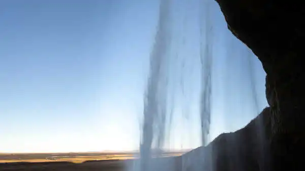 A waterfall is photographed from behind it at sunset