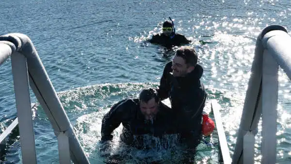 After a simulation of batptism, a diver is being pulled from the water