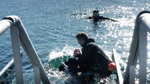 A man in being forced down into the water as if he was being baptised