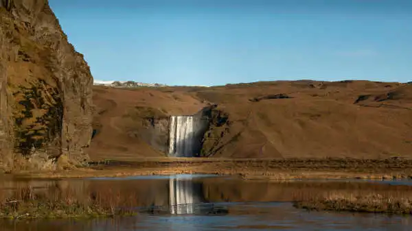 A tall, impressive waterfall is seen from a distance