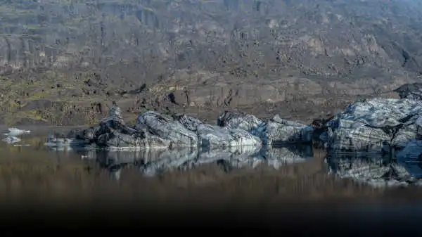 Ash covered glaciers reflecting on a glacier lake