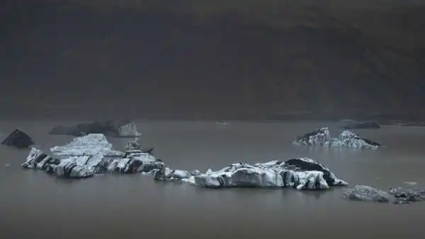 Icebergs floating on a glacier lake, during a misty day